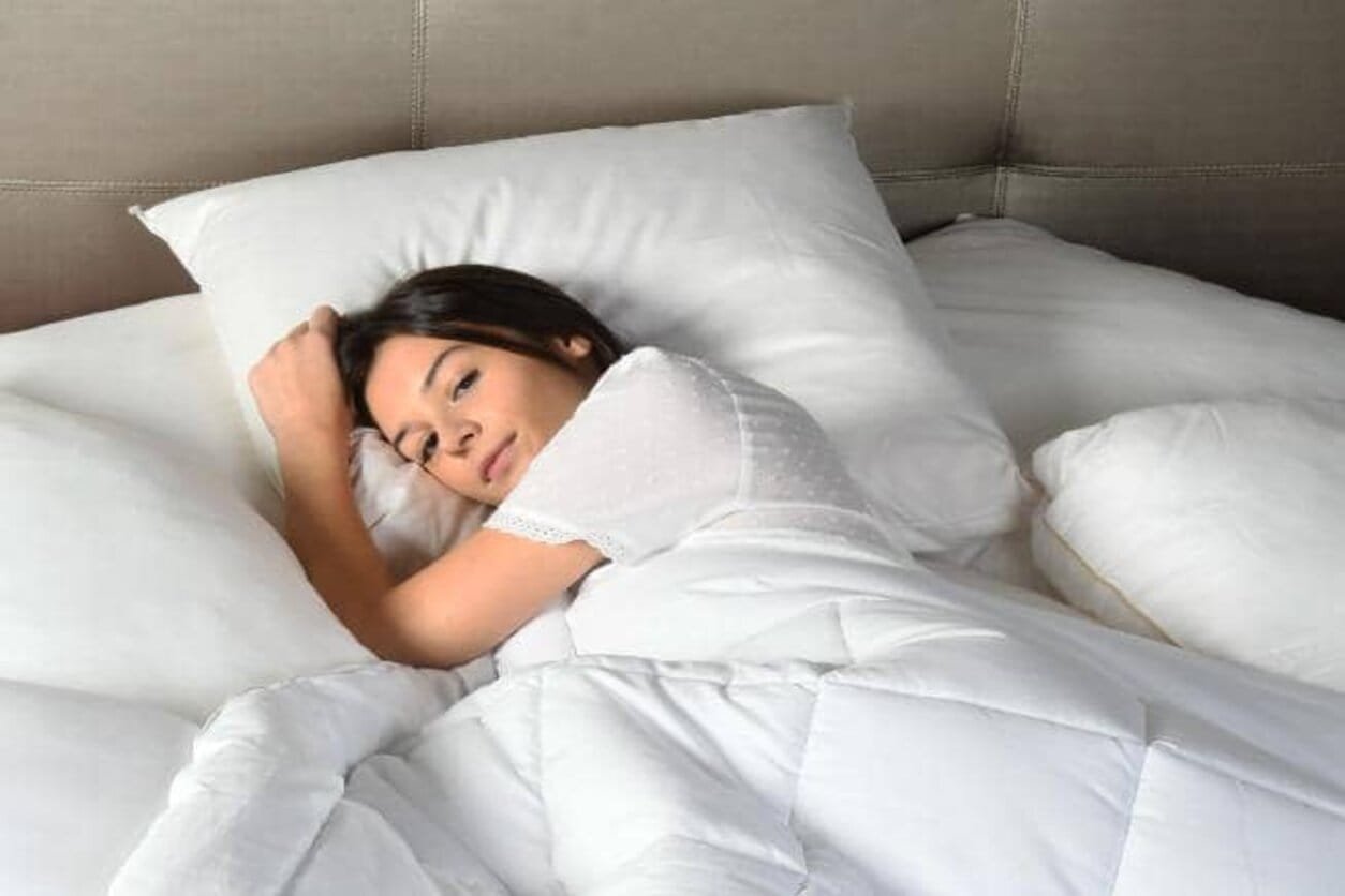 Une femme couverte avec une couette 220x240 dormant dans son lit